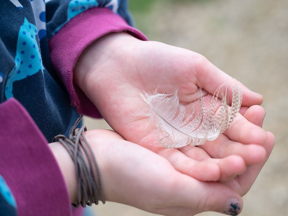 Kind mit Feder in der Hand