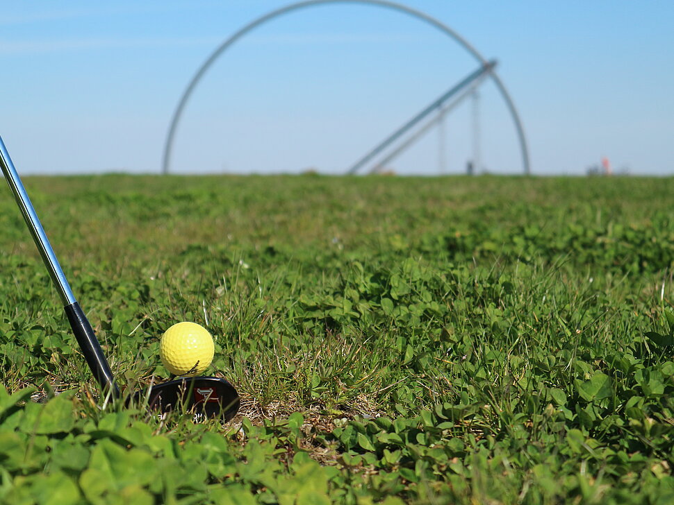 Nahaufnahme eines Golfschlägers mit Golfball vor dem Horizontobservatorium  