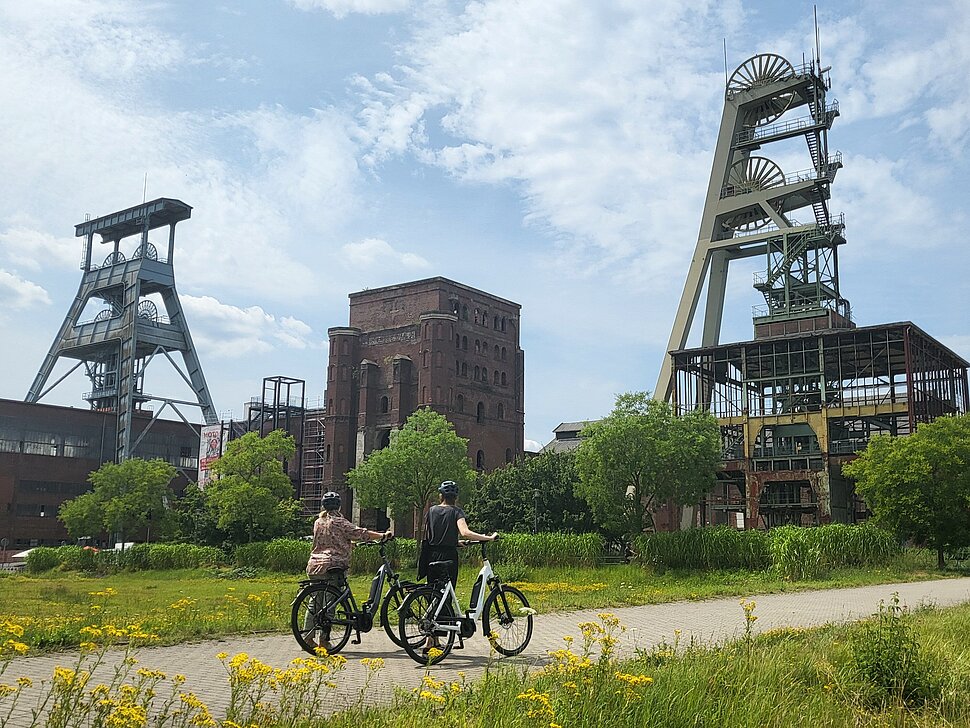 Zwei Personen fahren mit dem Fahrrad über das Gelände der ehemaligen Zeche Ewald.