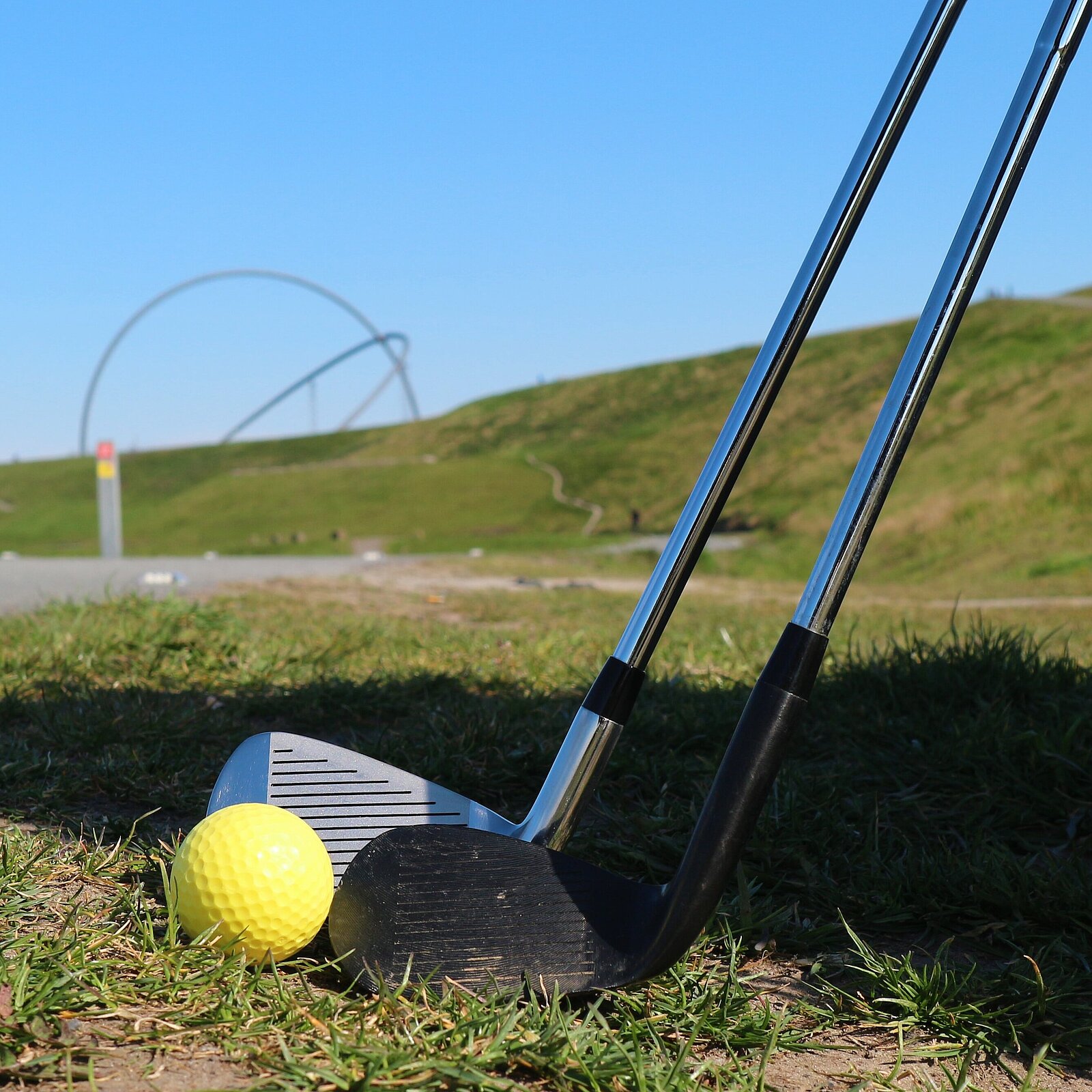 Zwei Crossgolfschläger mit Golfball vor dem entfernten Horizontobservatorium