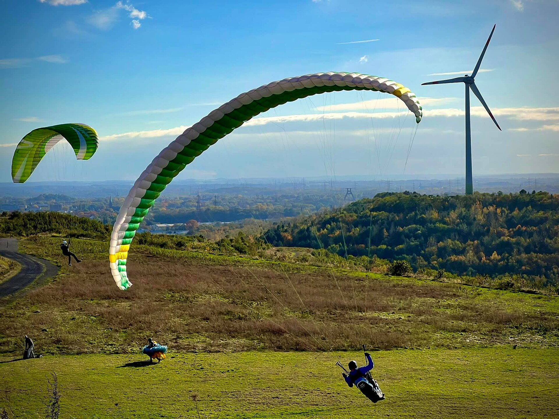 Mehrere Paraglider gleiten auf Westplateau Hoheward hinab