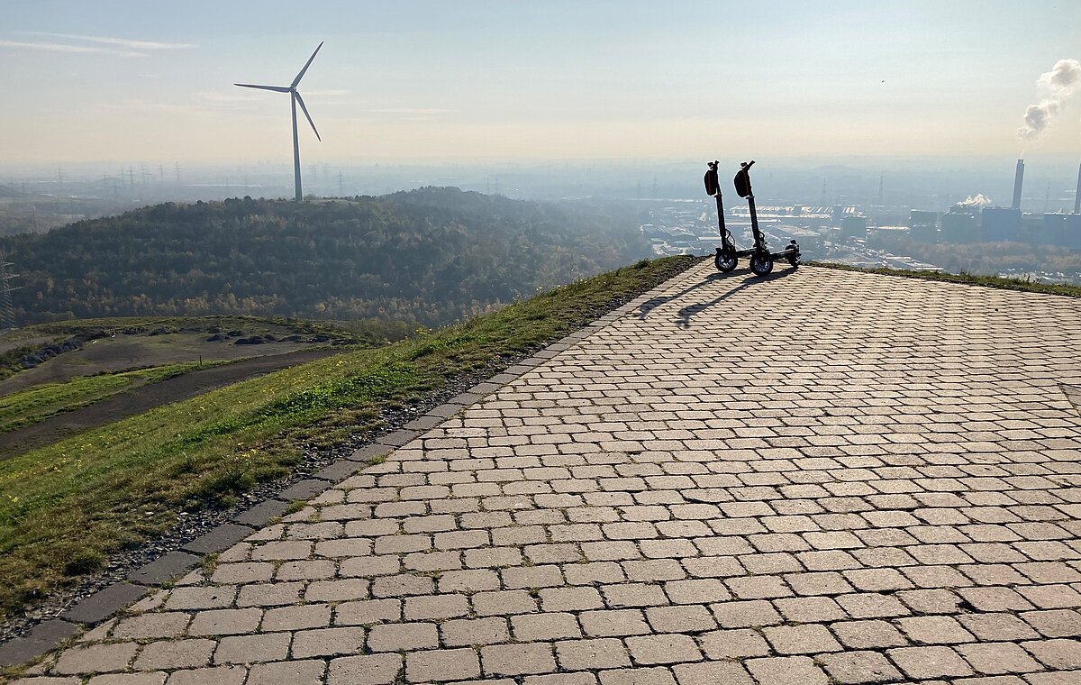 E-Scooter mit dem Windrad der Halde Hoppenbruch