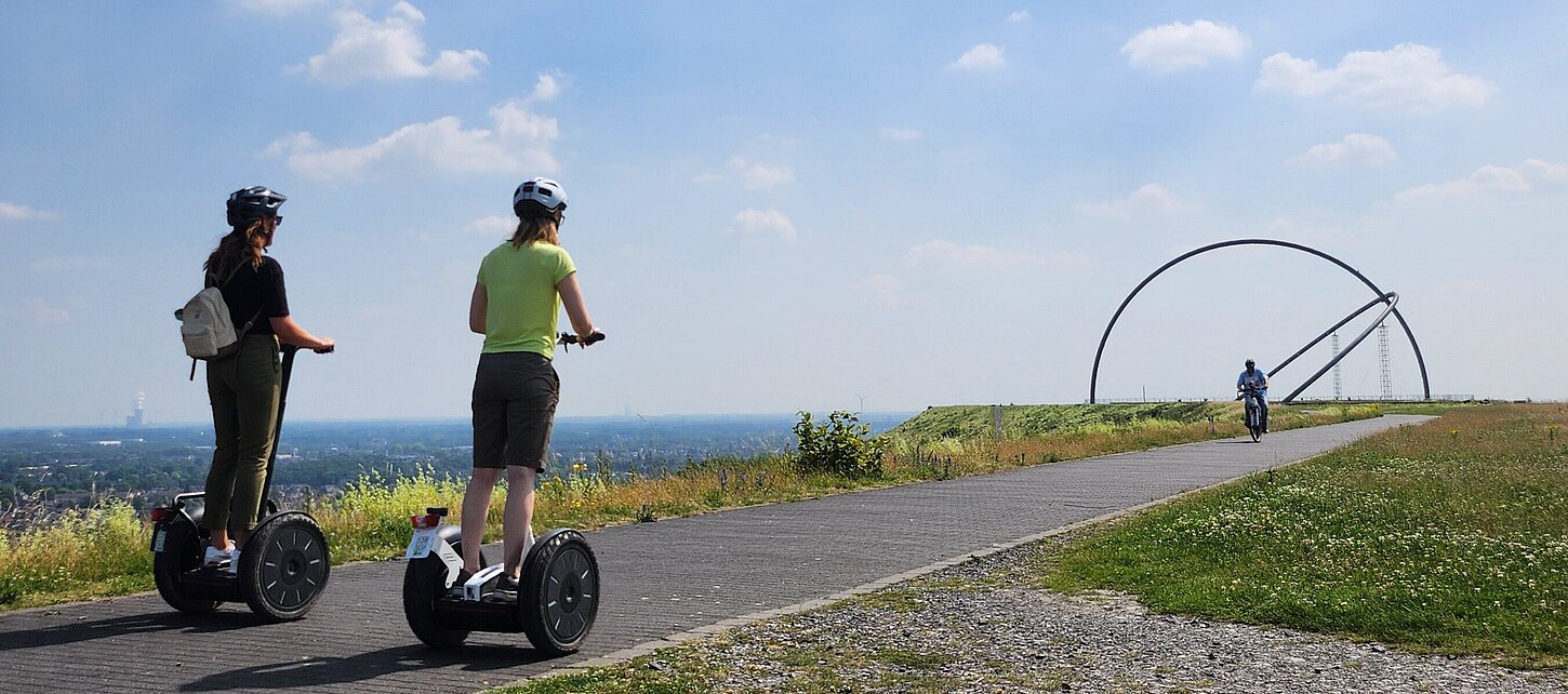 Zwei Segwayfahrer fahren in Richtung des Horizontobservatoriums auf der Halde Hoheward.