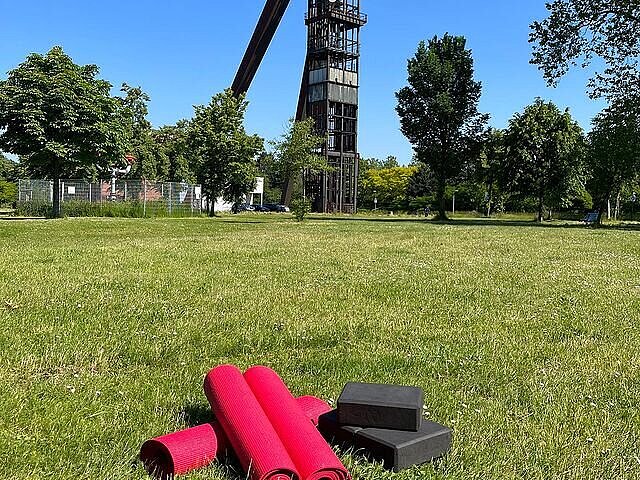 Yogamatten liegen auf der Wiese vor Schachtgerüst Recklinghausen II