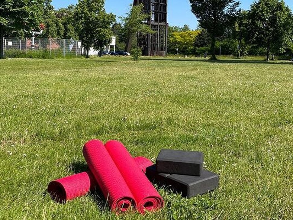 Yogamatten liegen auf der Wiese vor Schachtgerüst Recklinghausen II