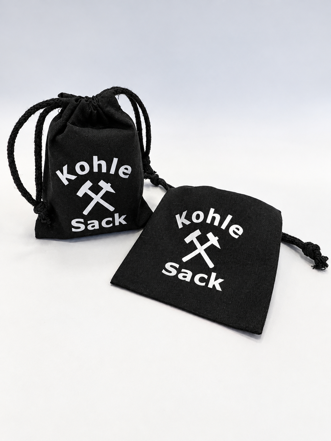 Kleine, schwarze Kohlesäckchen mit weißer Aufschift "Kohlesack"